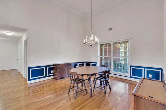 a dining room with wooden floor a chandelier a wooden table and chairs