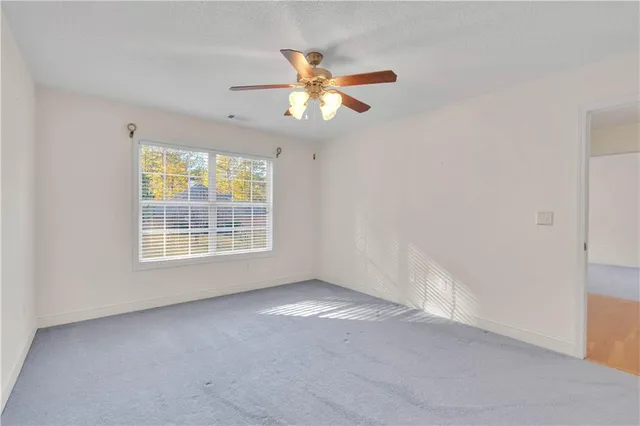 a view of an empty room with window and chandelier fan