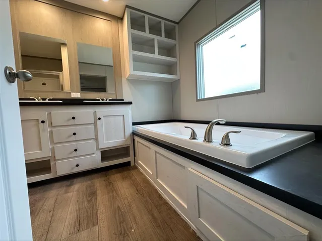 an empty room with wooden floor cabinet and windows