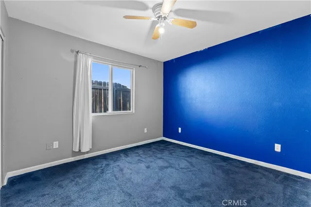 an empty room with windows and fan