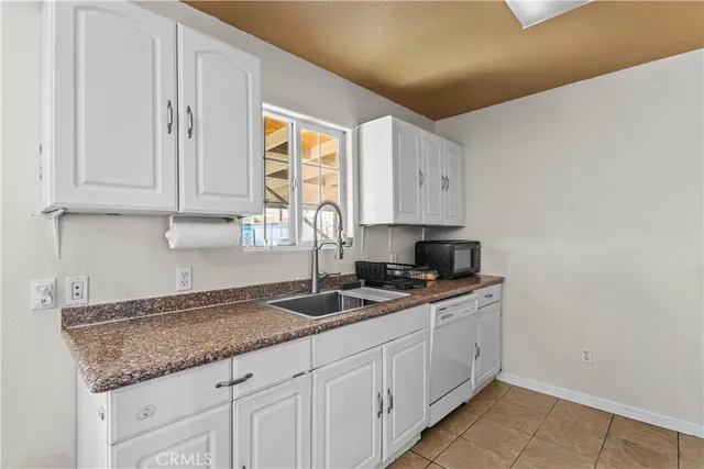 a kitchen with granite countertop white cabinets and a sink