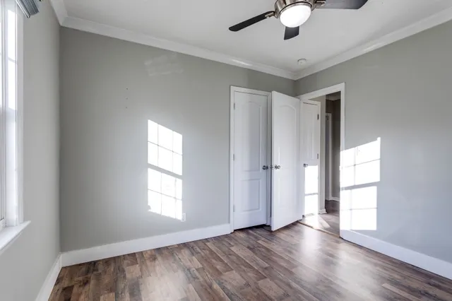 a view of empty room with wooden floor and fan
