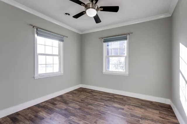 an empty room with wooden floor cabinet and windows