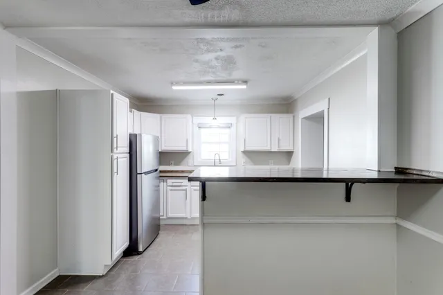 a view of an empty room with a window and chandelier fan