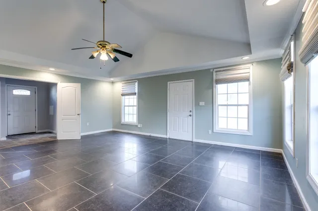a view of a livingroom with a chandelier fan and windows