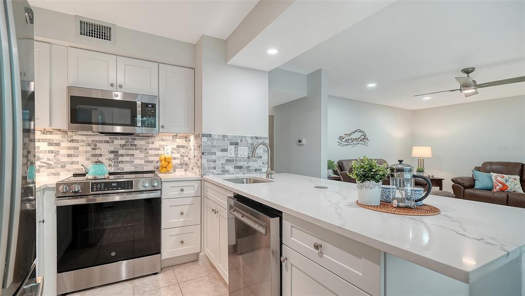 5950 Midnight Pass Road, Unit 201 Sarasota, FL 34242 - Photo 11 of 36 a kitchen with a sink stove and microwave