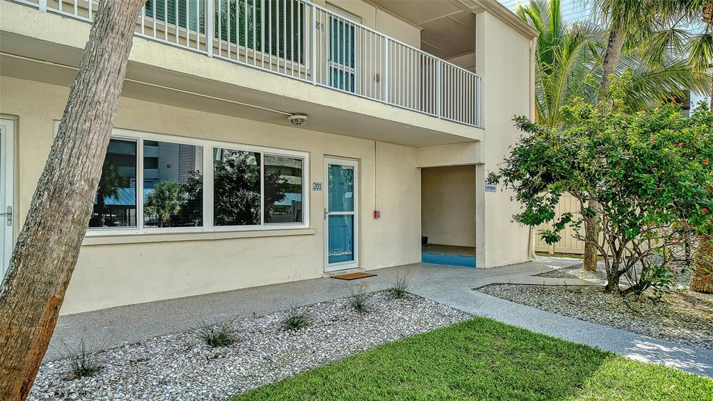 5950 Midnight Pass Road, Unit 201 Sarasota, FL 34242 - Photo 2 of 36 a front view of a house with a garden