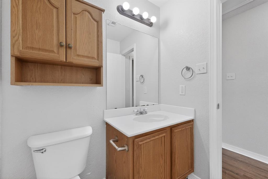 3401 Newgate Street Midlothian, TX 76065 - Photo 18 of 34 Bathroom vanity with a white countertop and integrated sink, complemented by a wood-finish cabinet and an overhead mirror