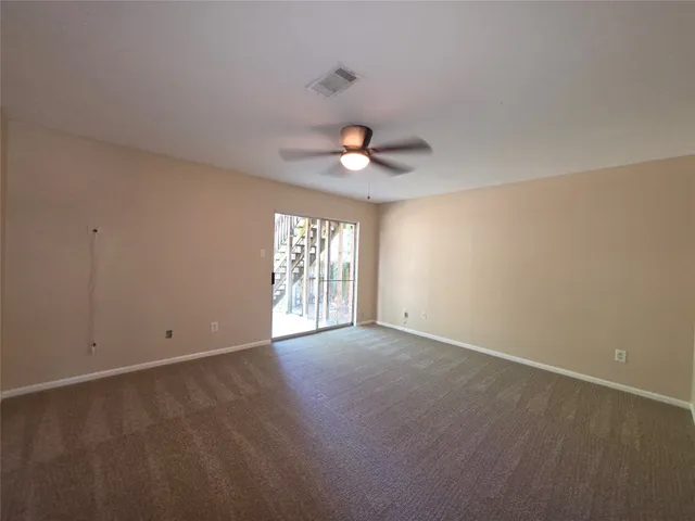 an empty room with windows and a ceiling fan