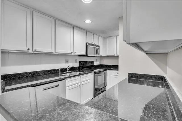 a kitchen with granite countertop white cabinets and stainless steel appliances