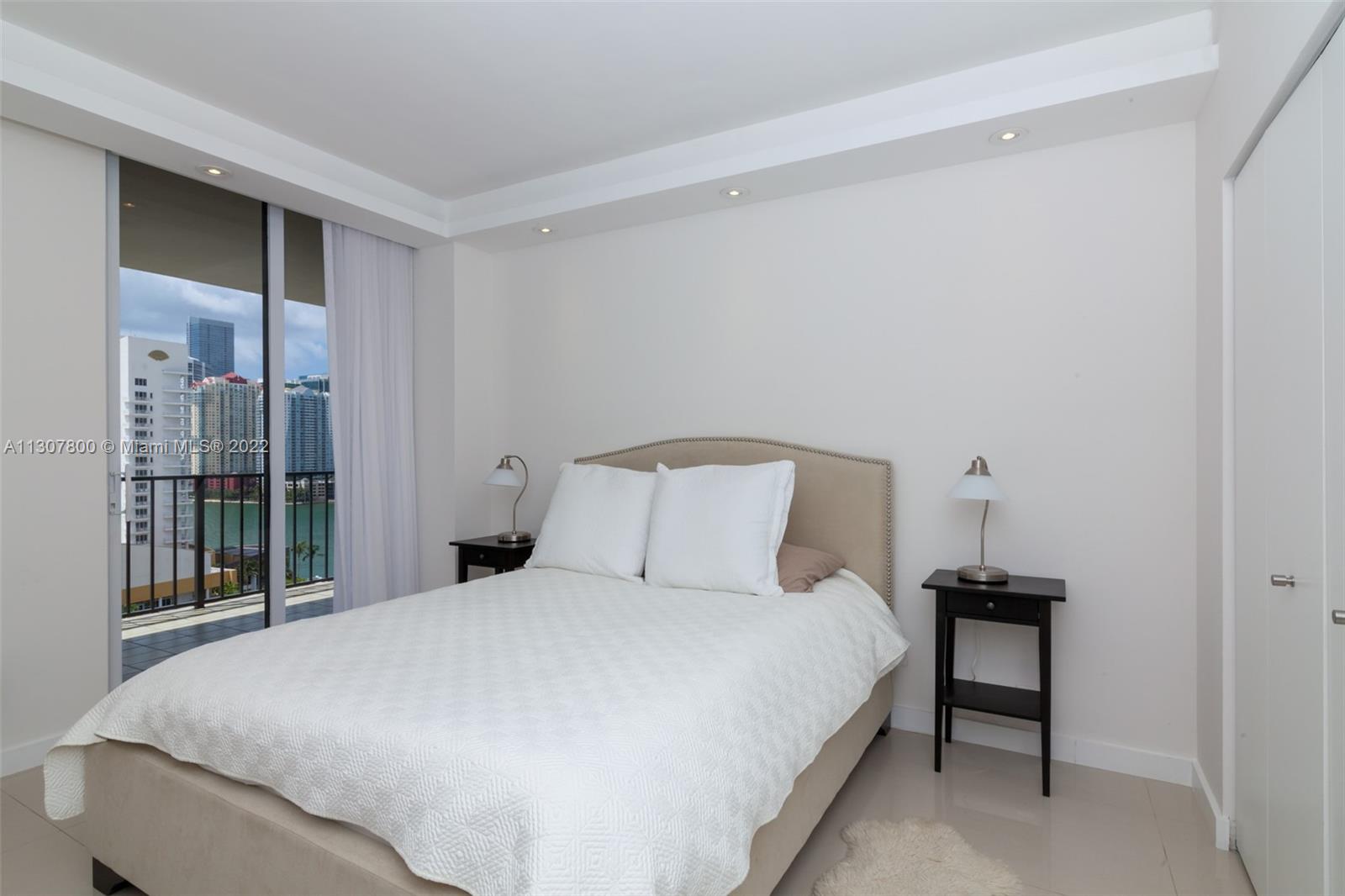 520 Brickell Key Drive, Unit A1603 Miami, FL 33131 - Photo 20 of 27 a large bed sitting in a bedroom next to a window
