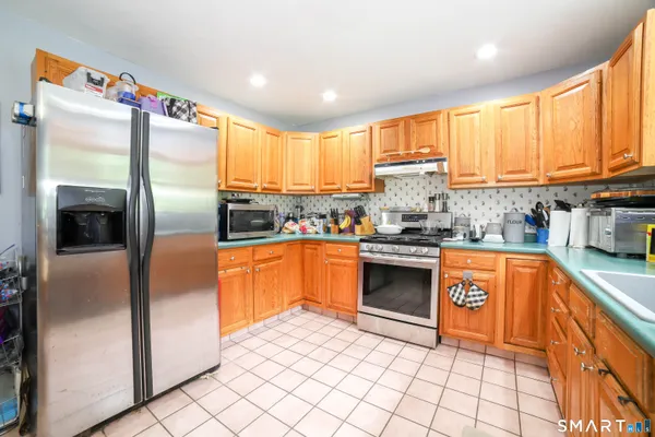 a kitchen with stainless steel appliances granite countertop a refrigerator a sink dishwasher a stove with white cabinets and wooden floor