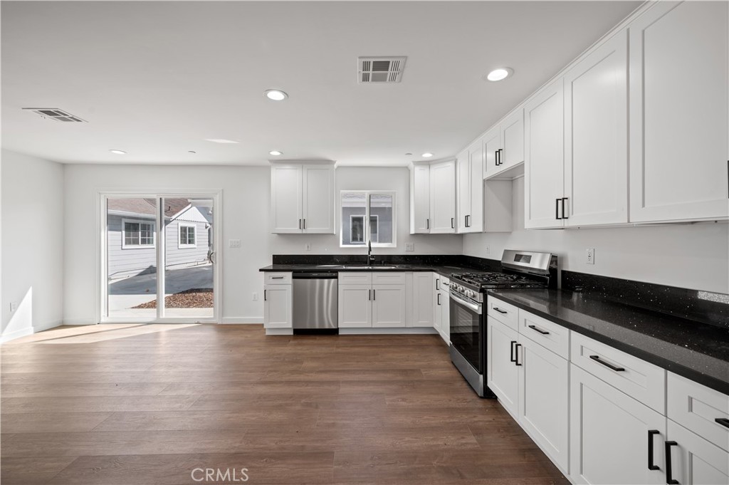 7445 Balcom Avenue Reseda, CA 91335 - Photo 30 of 73 a large white kitchen with stainless steel appliances granite countertop a stove a sink a refrigerator white cabinets and wooden floor