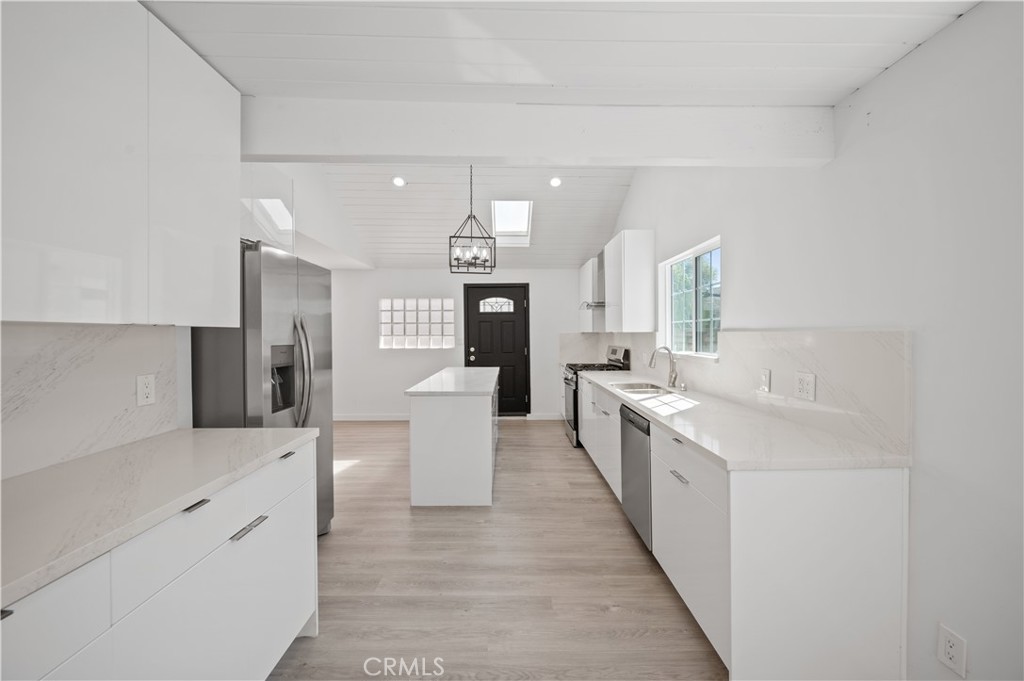 7445 Balcom Avenue Reseda, CA 91335 - Photo 49 of 73 a large white kitchen with a sink and dishwasher a stove top oven with wooden floor