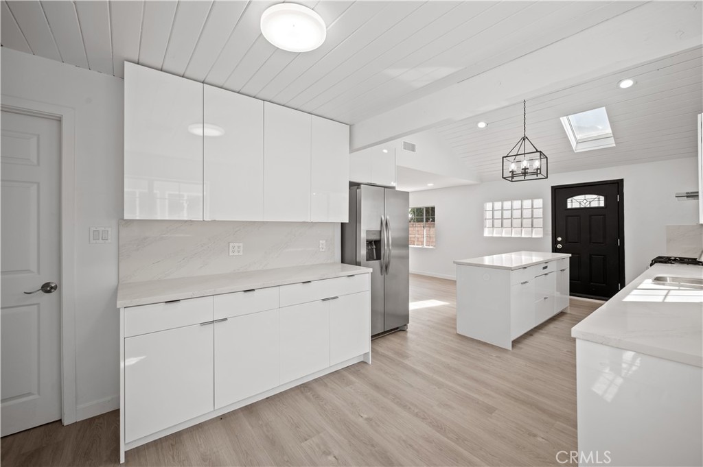 7445 Balcom Avenue Reseda, CA 91335 - Photo 50 of 73 a large white kitchen with a refrigerator a sink dishwasher a stove and white cabinets with wooden floor