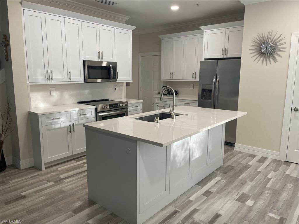 a kitchen with stainless steel appliances a sink a stove a refrigerator and cabinets