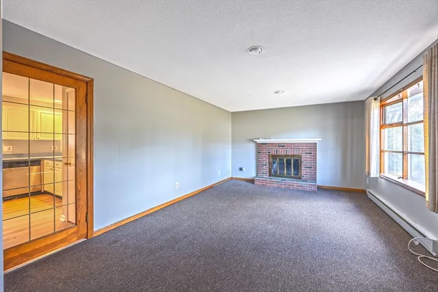 a view of an empty room with a window and a kitchen