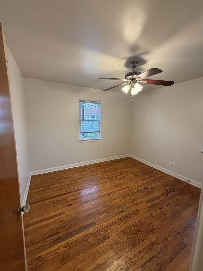 312 East 83rd Street, Unit 1 Chicago, IL 60619 - Photo 18 of 18 a view of an empty room with wooden floor and a ceiling fan