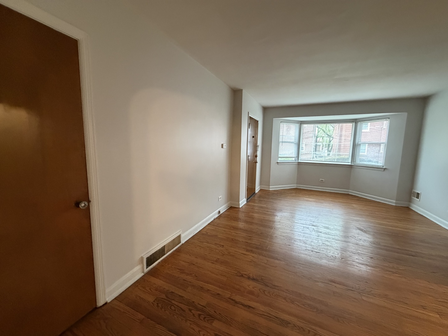 312 East 83rd Street, Unit 1 Chicago, IL 60619 - Photo 4 of 18 an empty room with wooden floor and windows