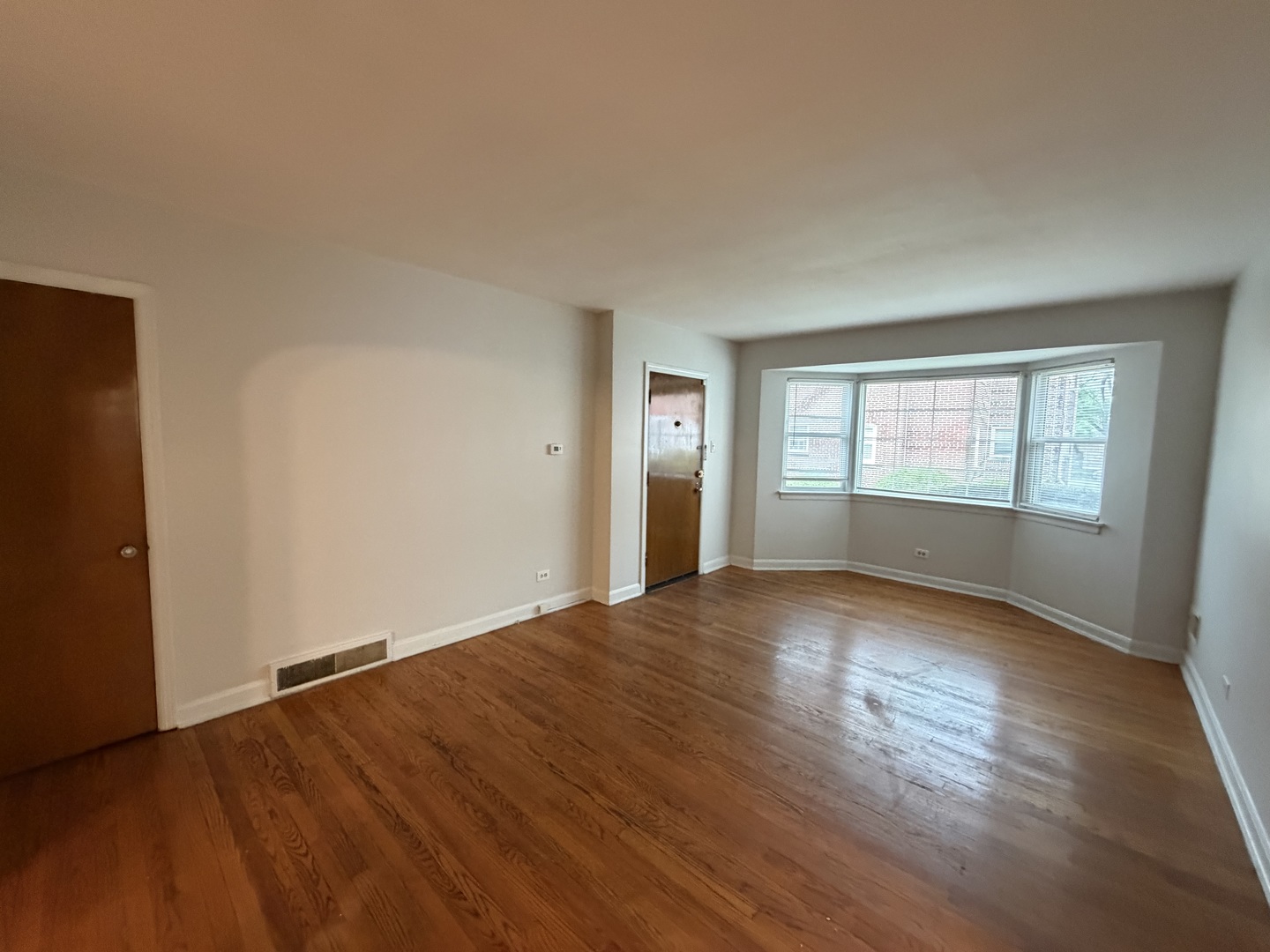 312 East 83rd Street, Unit 1 Chicago, IL 60619 - Photo 5 of 18 an empty room with wooden floor and windows