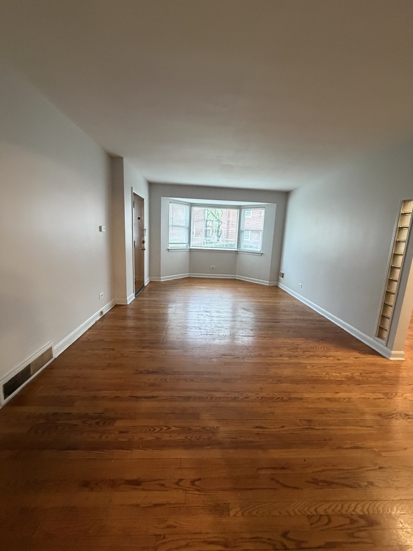 312 East 83rd Street, Unit 1 Chicago, IL 60619 - Photo 7 of 18 a view of an empty room with window and wooden floor