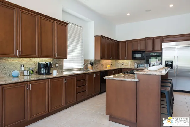 a kitchen with kitchen island granite countertop wooden cabinets stainless steel appliances a sink and a window