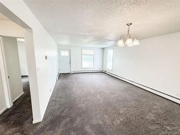 an empty room with a chandelier fan and windows