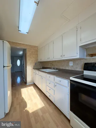 a kitchen with granite countertop a stove a sink and white cabinets