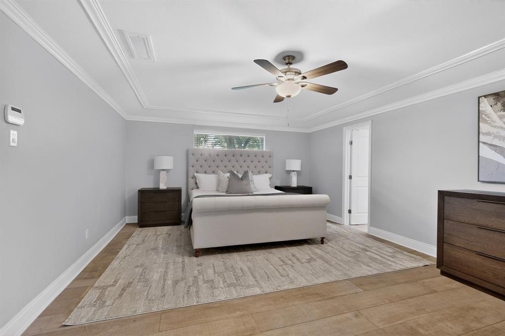 7631 Meadow Road Dallas, TX 75230 - Photo 15 of 40 A spacious primary bedroom showcasing a ceiling fan, a tall window and access to the patio at the back.
