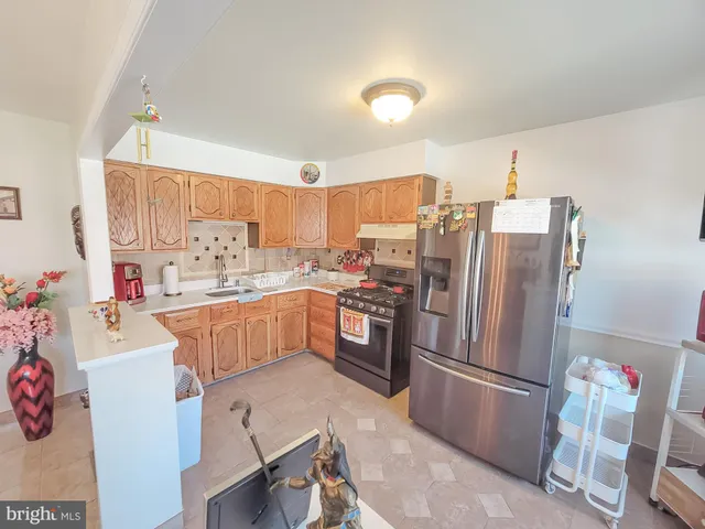 a kitchen with stainless steel appliances a refrigerator a sink a stove and chairs