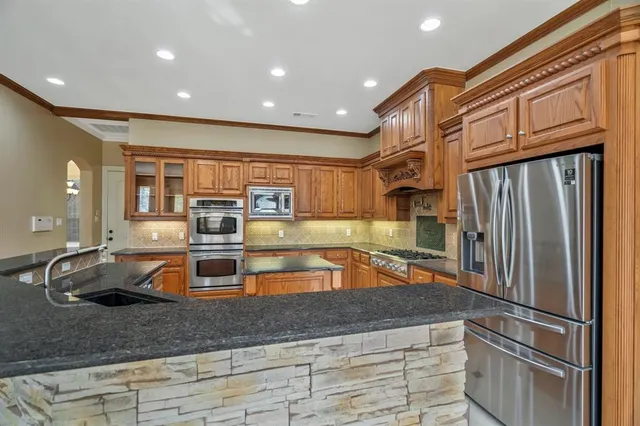 a kitchen with stainless steel appliances granite countertop a refrigerator and a sink