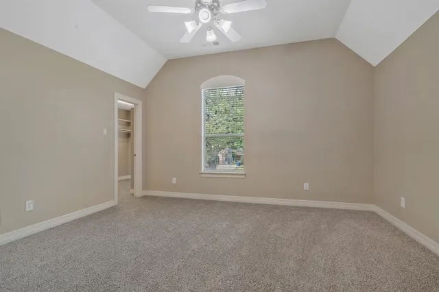 an empty room with windows and chandelier fan