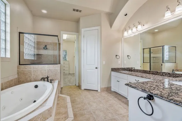 a bathroom with a granite countertop tub sink shower and mirror