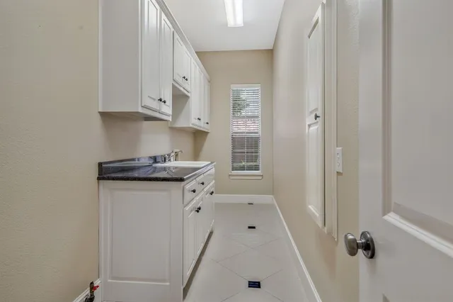 a kitchen with white cabinets and sink
