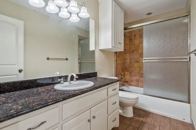 a bathroom with a granite countertop sink a toilet and shower
