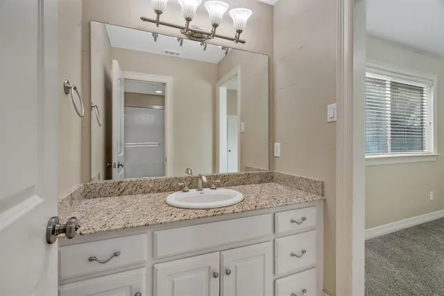 a bathroom with a granite countertop sink a toilet and shower
