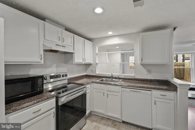a kitchen with white cabinets appliances and a sink