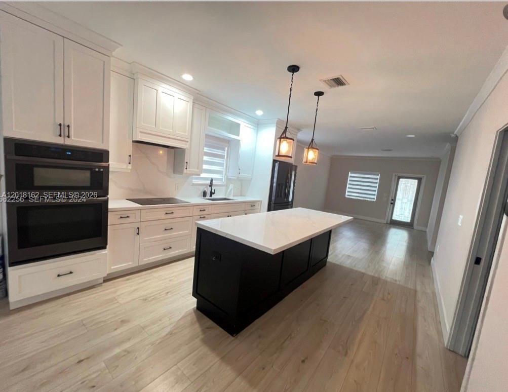 897 East 20th Street Hialeah, FL 33013 - Photo 4 of 13 a kitchen with stainless steel appliances a kitchen island hardwood floor sink stove dining table chairs and cabinets
