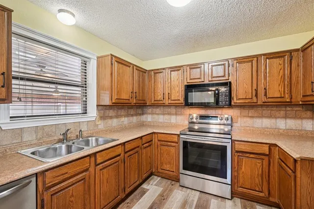 a kitchen with stainless steel appliances granite countertop a sink stove cabinets and wooden floor