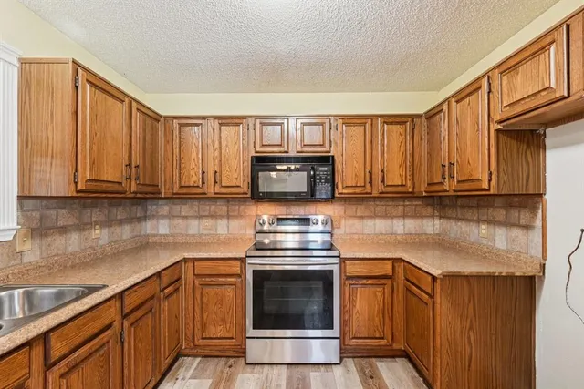 a kitchen with granite countertop a stove a sink and cabinets