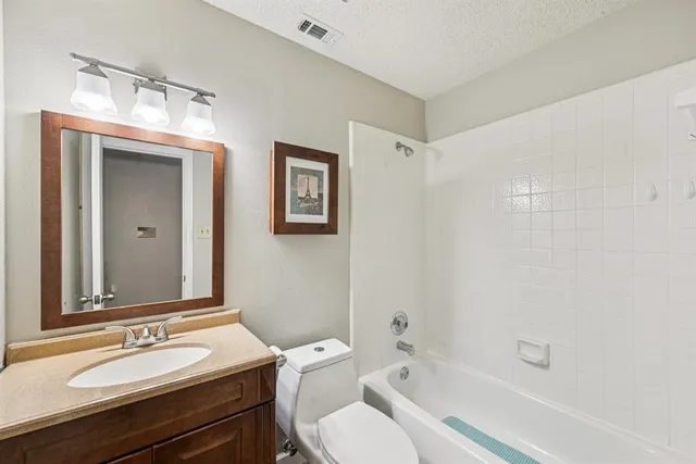a bathroom with a granite countertop sink toilet a large mirror a bathtub and shower