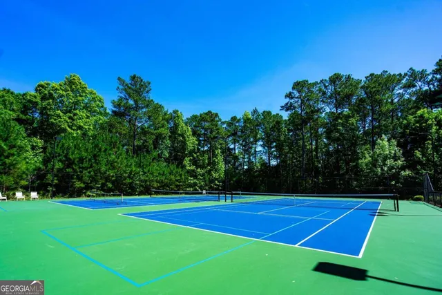 a view of a tennis ground with large trees
