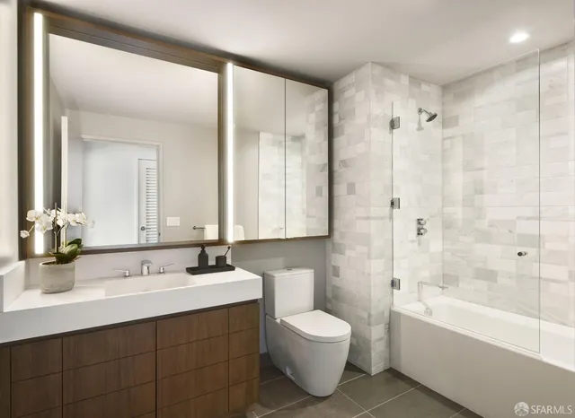 a bathroom with a bathtub shower sink vanity and toilet