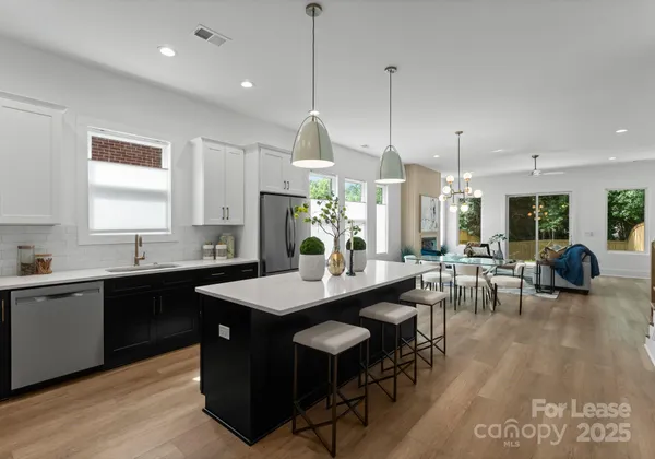 a kitchen with stainless steel appliances kitchen island granite countertop a table chairs and a wooden floor