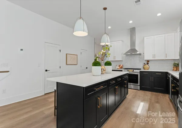 a kitchen with stainless steel appliances granite countertop a sink a stove and a wooden floors