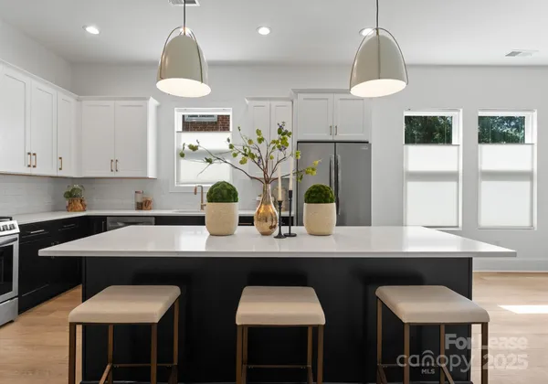 a kitchen with stainless steel appliances a dining table chairs and a refrigerator