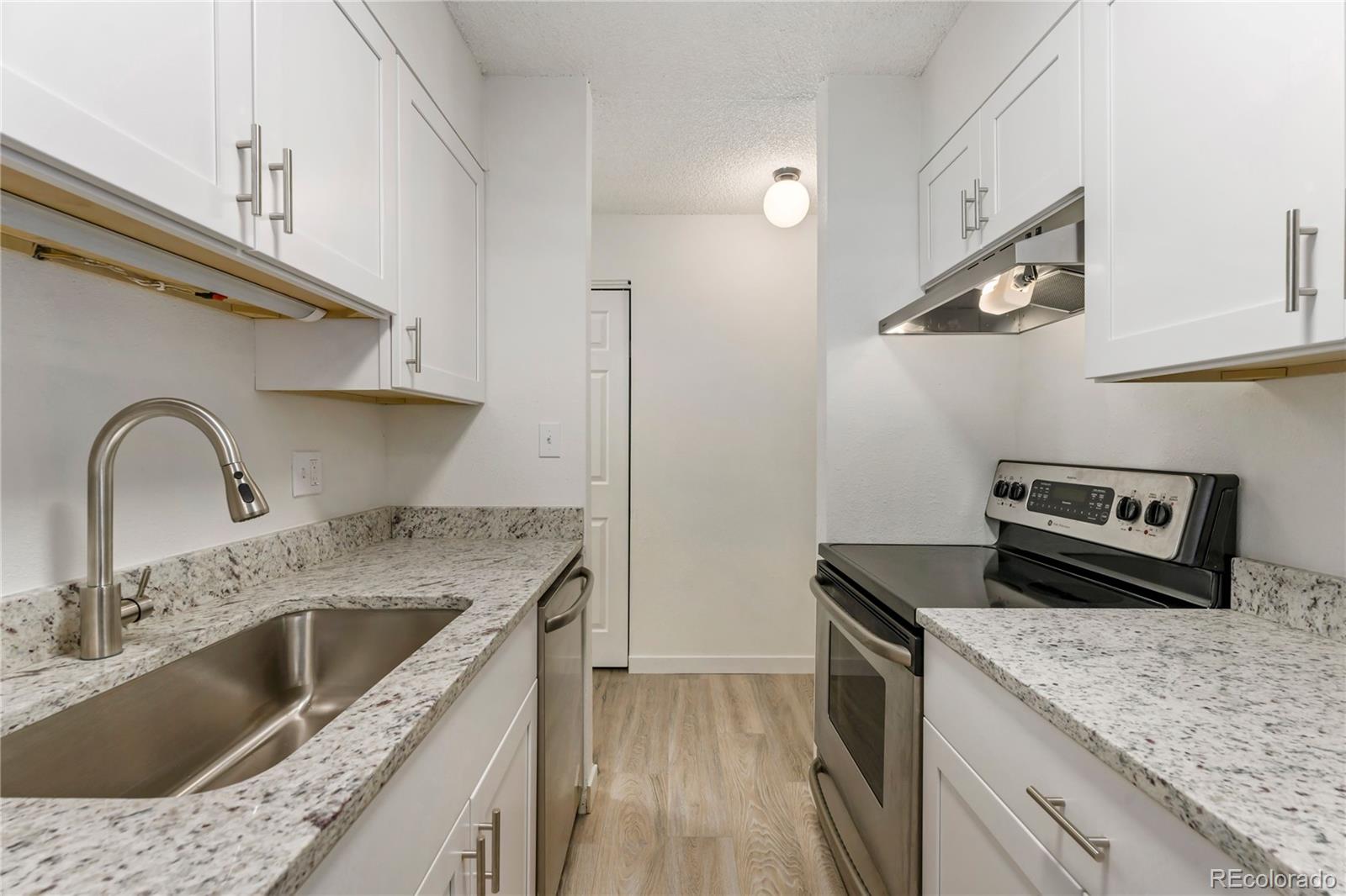 209 East Highline Circle, Unit 108 Centennial, CO 80122 - Photo 6 of 22 a kitchen with granite countertop a sink and a stove top oven