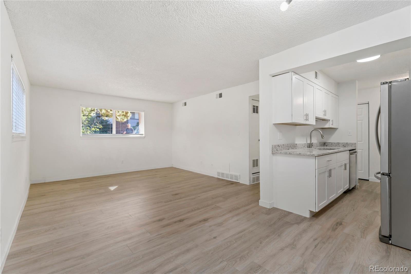 209 East Highline Circle, Unit 108 Centennial, CO 80122 - Photo 7 of 22 a kitchen with granite countertop a refrigerator and a stove top oven