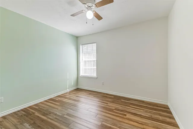 a view of a room with wooden floor and a ceiling fan