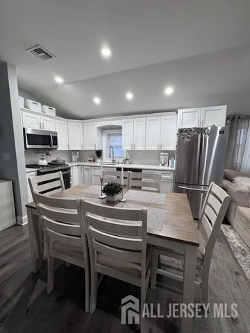 a kitchen with stainless steel appliances a table chairs refrigerator and microwave
